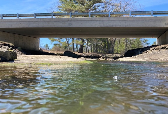 A bridge over a shallow river and rocks on a sunny day.